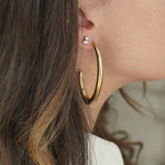 Close-up of a person wearing gold hoop earrings with a neutral background Nikki E Designs Ada Studs Gold Ear Stack