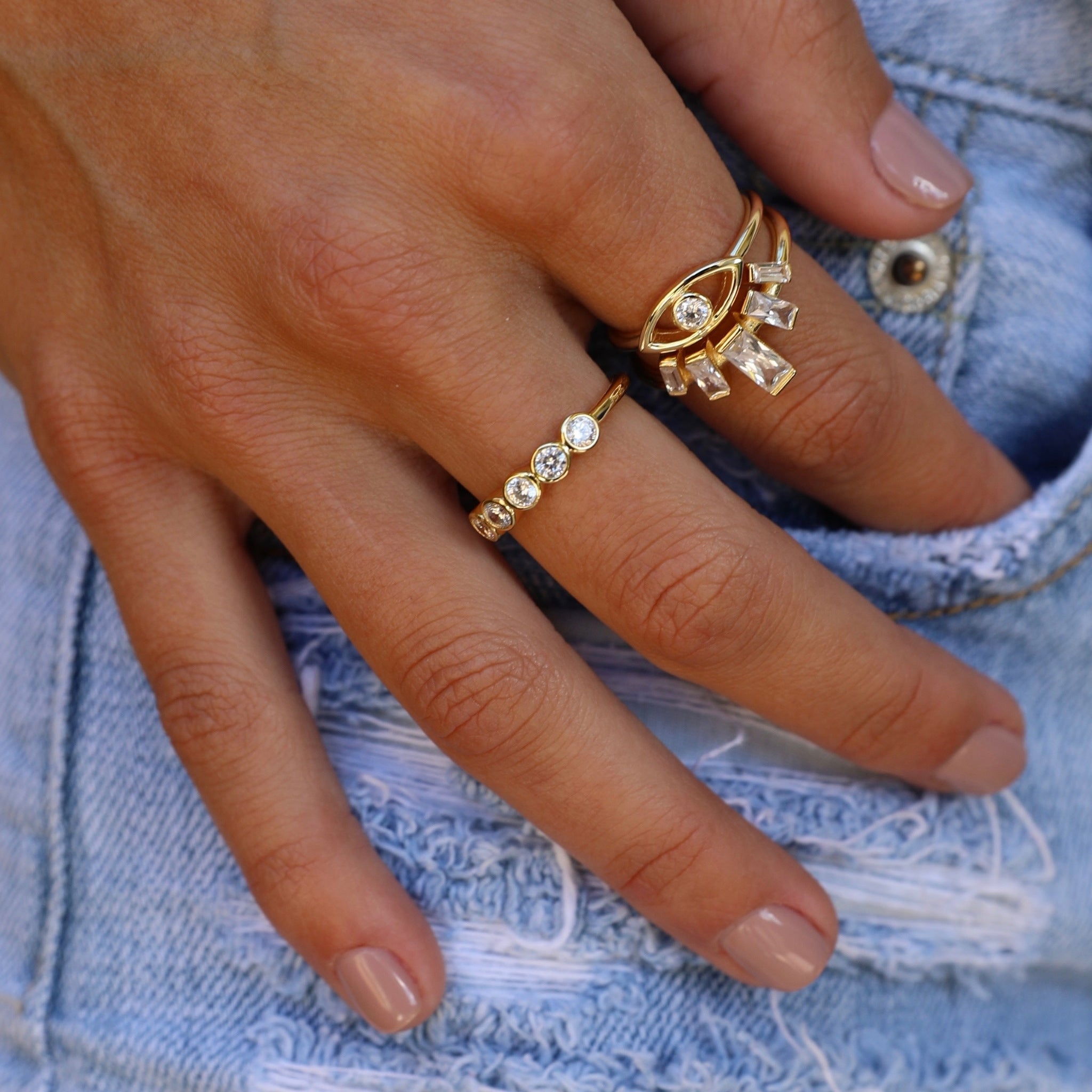 Gold baguette crown ring stacked with Evil Eye ring on hand in denim – Nikki E. Designs